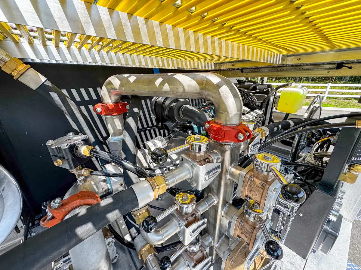 Underbody equipment close-up beneath rear deck showing hydraulic hardware.